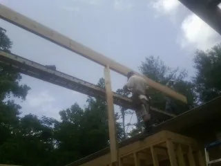 Carpenter setting a ridge beam over a new addition frame — Ice Dam Removal by Roofing Brothers in Harrellsville