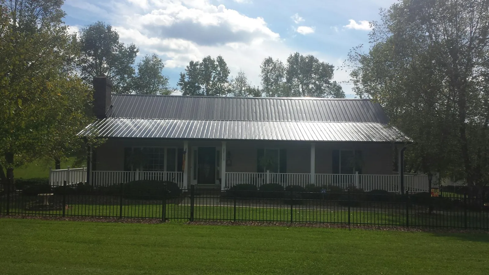 Gray metal roof on a brick ranch with a full width front porch — Gutter Guard Installation work by our crew in Harrellsville