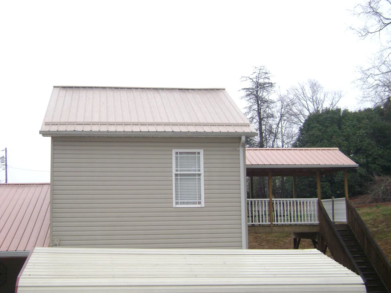 Tan metal roofs on a two story addition and attached porch, from a Roof Replacement job in Harrellsville