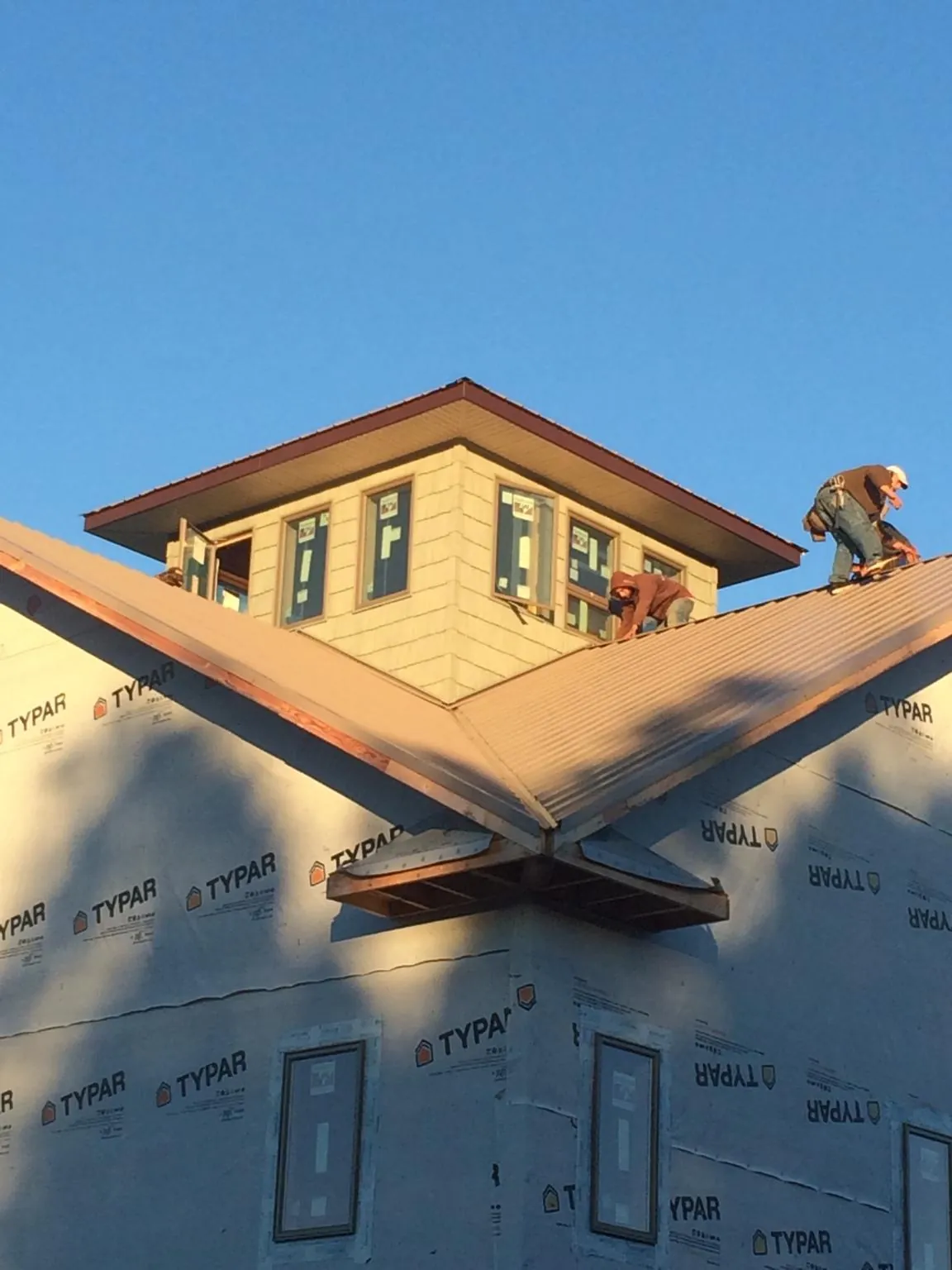 Roofers working around a rooftop cupola on a new metal roof at sunset — Roof Waterproofing in Harrellsville by Roofing Brothers
